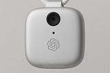Image of a squarish white device with a camera and an OpenAI logo on the front. It’s suspended by a white piece of rope. Overall look is that of an Apple product.