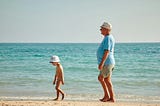 A child and an old man on the beach.