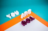A bold graphic design with the words “You Are You.” The words tumble around part of a square (right angle) framed in orange.