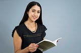 Woman wearing a black shirt and holding a book against a blue background