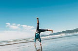 brown-haired girl turning cartwheels at low tide