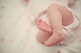 Baby in diapers lies in a bassinet.