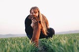 Lady kissing a dog in a green field