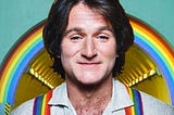 Robin Williams smiling with rainbow suspenders/braces.