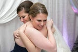 2 daughters hugging on a wedding day