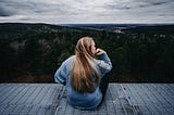 a woman looks out pensively over a landscape