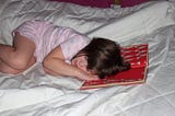 little white girl (author’s daughter) with brown hair asleep in bed with her head resting on an open Dr. Seuss book