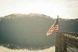 american flag on fence with hazy forest in background