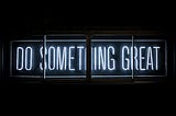Dark LED-Sign saying in light blue font “Do something great”