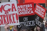 An image of writers holding signs during a strike initiated by the Writers Guild of America