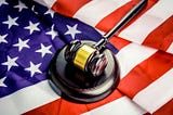 A judge’s gavel and hammer resting on top of the red, white and blue flag of the United States of America.