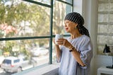 Portrait of senior Asian woman with cancer looking out window with hopeful expression