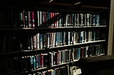 Several shelfs displaying a line of books presumably in a library