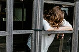 Young teenage girl leaning on what looks like a window frame