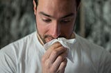 Man holding a hanckerchief against his nose