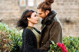 A couple hugging, with the girl holding a bouquet of roses