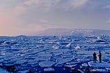 Two people stare out at a sea of broken ice.