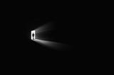 small image of a man in a doorway surrounded by darkness