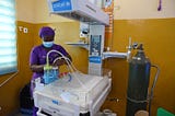 A nurse, clad in a purple uniform, assembles medical equipment for the tiniest of patients, newborns.