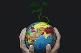 Gloved hands tenderly holding a globe of the Earth with a seedling shooting out of the top of it.