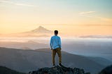 Person standing on top of a mountain looking out over the range