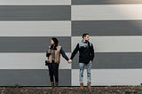 A man and a woman holding hands and looking in opposite directions