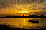 Boat in the waters overlooking the setting sun