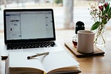 An open laptop and a diary on a desk