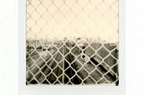 sepia toned polaroid picture of train tracks through fence