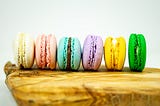 Six macarons on a wooden table.