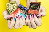 A pair of hands holding a bunch of condoms.