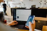 A man types on his laptop and his cell phone.