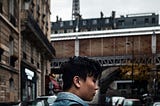 An asian man walking around in a city with a backpack