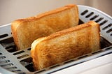 Photo of two slices of toasted bread in toaster.