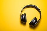 A pair of black headphones against a yellow background