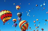 Many hot air balloons in a blue sky