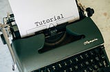 A green typewriter with a page showing the word “Tutorial”