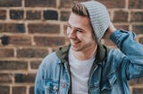 A smiling man wearing a beanie and a denim jacket