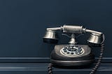 An image with a blue background, and black, old-fashioned telephone on the right.