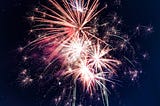 Fireworks explode in the center of the frame. The author has used this image to show the ending of one year and the beginning of new one.