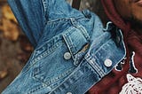 Middle aged man in blue denim jacket, and brown sweaters lies down closing his eyes reminiscing peace of mind and solitude.