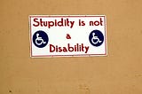 A photo of a poster with handicap symbols that says, “Stupidity is not a Disability”