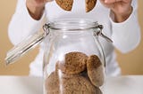 Close-up of woman taking a cookie out of a cookie jar.