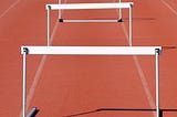 A picture of hurdles lined up in a lane on a track.