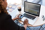 Woman viewing her laptop with a cup of coffee