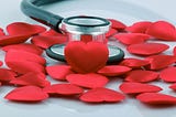 A stethoscope surrounded by red paper hearts.