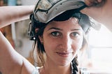 Photo of a woman maker lifting a welding helmet to smile at the camera. Most crafters and makers on handmade marketplaces are women.