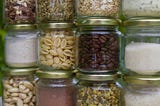 Stacks of clear glass jars with various types of food inside.
