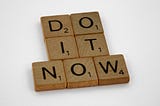 Scrabble tiles spelling out “Do it now”