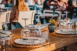 Picture of a wooden table with fine cutlery and plates representing fine dining